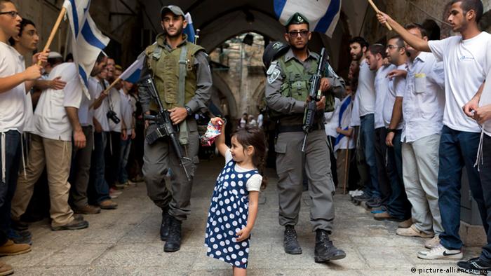 A little girl stands with border police