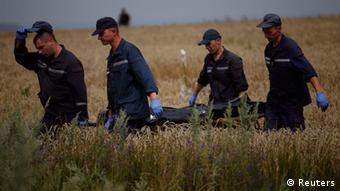 Men carrying a body on a field. (Photo: REUTERS/Maxim Zmeyev)
