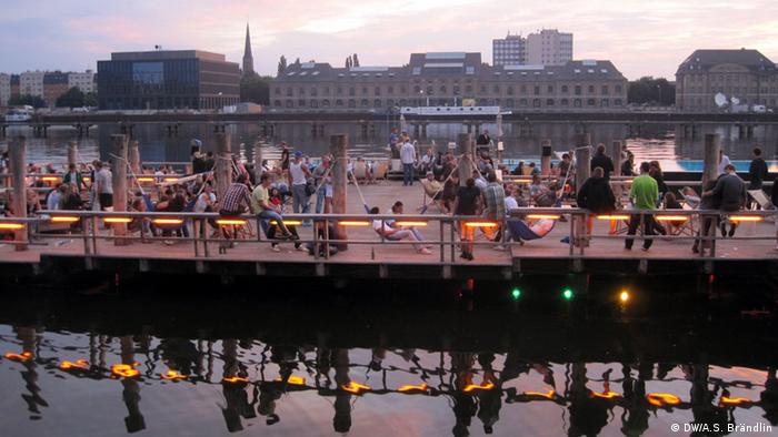 Berlin residents enjoying the sunrise after a night of clubbing at Badeschiff, Copyright: DW / Anne-Sophie Brändlin