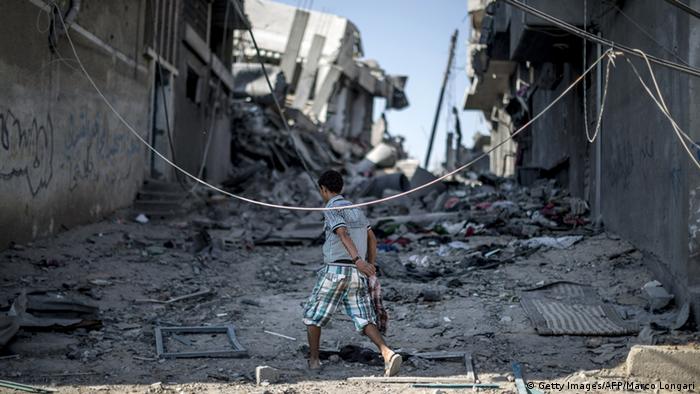 A Palestinian youth wanders through destroyed houses