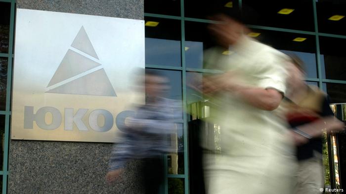 People walk by the Yukos oil company headquarters in Moscow on July 8, 2004