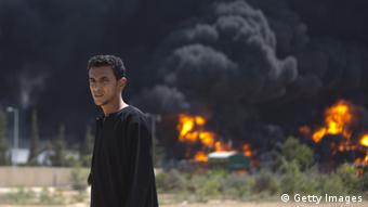 Power station in Gaza on fire, with a young man standing in the foreground. (Photo: MAHMUD HAMS/AFP/Getty Images)
