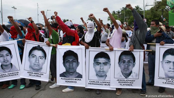 At a protest in Mexico, people hold up large black and white photographs of the missing students 