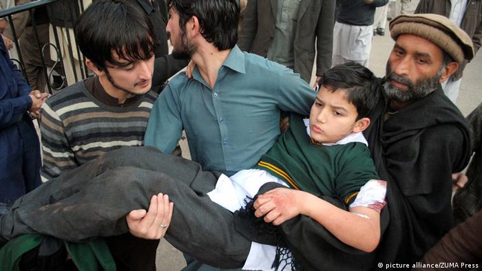 A wounded child is carried away from the scene. At least 100 people, mostly children, have been killed in a Taliban assault on an army-run school, officials say