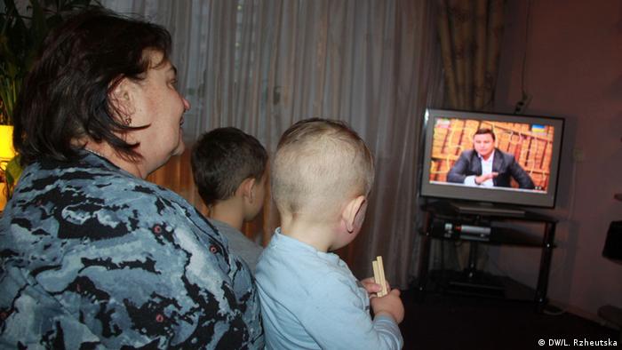 Женщина с детьми смотрит телевизор