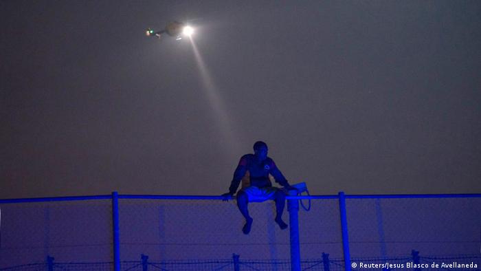 Refugiado busca superar la frontera en Melilla, enclave español en África. 