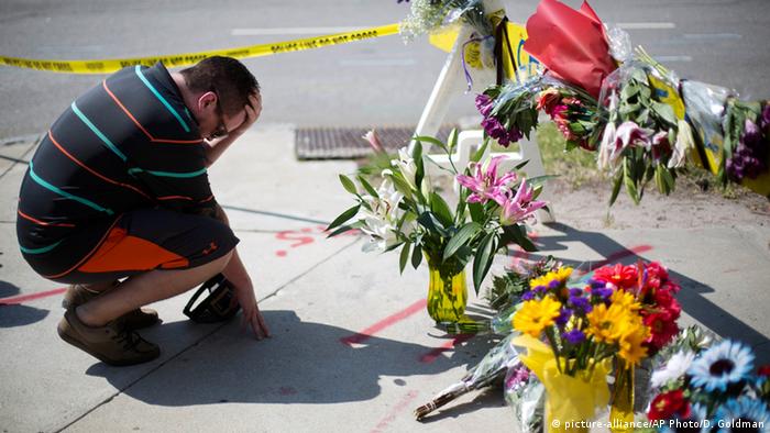 Мужчина возлагает цветы возле церкви, где произошла стрельба