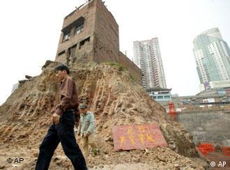 ** FILE ** People walk past a house sitting on a mound in the middle of a construction site in Chongqing, in southwest China, Thursday, March 22, 2007. The family who occupy the house refused an offer of compensation from the land developer, but was ordered by the local court to move out. The Chinese couple who own it have stirred up an Internet and media frenzy over their fight to keep their home and restaurant from being razed by developers, in what is seen as the first major test of a newly passed private property law. (AP Photo/EyePress, File) ** CHINA OUT **