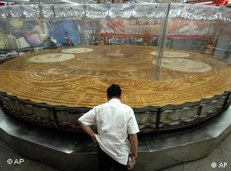 A chef gives a final check on the freshly baked China's largest moon cake in Shenyang, northeastern China's Liaoning province, Tuesday, Aug. 21, 2007. The moon cake, measures 8.15 meters diameter, 20 centimeters in thick, weighing 12.98 tons, and having 10 flavors, was made of one ton's flour and 12 tons stuffing and baked for 10 hours. (AP Photo) ** CHINA OUT **