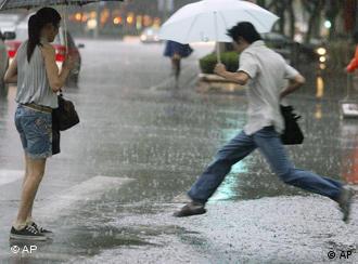 A pedestrian jumps over a flooded road as it rains in Shanghai, eastern China, Tuesday, Sept. 18, 2007. China's commercial center of Shanghai was evacuating 200,000 people on Tuesday ahead of the expected arrival of Typhoon Wipha, potentially the most destructive storm to hit the city in a decade. (AP Photo/EyePress) CHINA OUT 