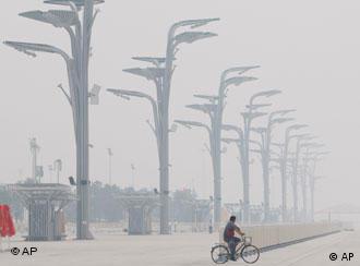 Haze is seen as a Chinese rides his bike past some lamp posts at Olympic park outside the National stadium at the Beijing 2008 Olympics in Beijing, Monday, Aug.4, 2008. (AP Photo/Luca Bruno)