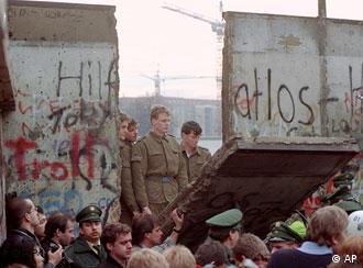 Восточногерманские пограничники смотрят сквозь пролом в стене
