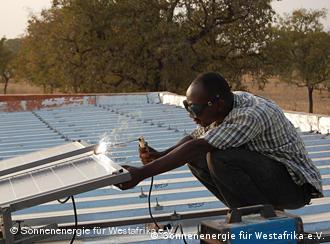 A worker in Burkina Faso welds a solar energy facility 