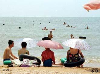 Chinese relax on a public beach at Beidaihe, a seaside resort east of Beijing, Sunday, Aug. 6, 2000. This quiet seaside haven is where President Jiang Zemin and other Chinese leaders come for a few weeks each summer to escape the muggy capital 150 miles to the west and hammer out policies between dips in the polluted, green-blue Bohai Sea. (AP Photo/John Leicester)