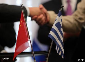 Business men shake hands behind a Chinese and a Greek flag during the signing ceremony of 11 private business deals and two state cooperation agreements for trade and cultural affairs between the two countries in Athens, Saturday, Oct. 2, 2010. Chinese Premier Wen Jiabao vowed Saturday to double trade with Greece within five years, and to buy Greek bonds when the crisis-hit country returns to international markets. (AP Photo/Petros Giannakouris)