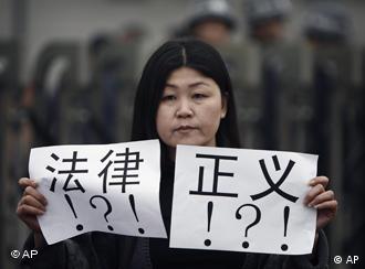 An activist holds papers bearing the words law and justice outside a court house during the trial of Zhao Lianhai in Beijing, Tuesday, March 30, 2010. Zhao Lianhai, who organized a support group for parents of children sickened in one of China's worst food safety scandals pleaded not guilty Tuesday to charges of inciting social disorder, his lawyer said. (AP Photo/Andy Wong)

