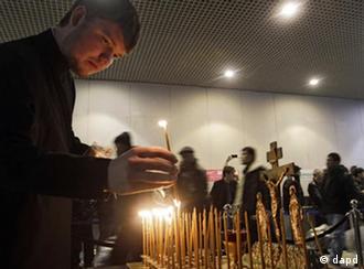 A clergyman lights candles at the site of a blast at Domodedovo airport near Moscow on Wednesday, Jan. 26, 2011. Security was tightened in Moscow on Tuesday, after a suicide bomber set off an explosion that ripped through Moscow's busiest airport on Monday. (Foto:Sergey Ponomarev/AP/dapd)