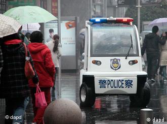 Police officers drive an electric police patrol car through a busy shopping street under the rain  in Shanghai, China, Sunday, March 6, 2011. (AP Photo/Eugene Hoshiko)