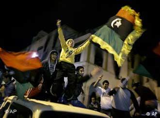 Youths on the roofs of vehicles waving pre-Gadhafi era Libyan flags now used by the opposition, ride through the streets at night in Benghazi, Libya Friday, April 1, 2011. In a sign the international airstrikes may be eroding Gadhafi's resilience, his government is trying to hold talks with the U.S., Britain and France in hopes of ending the air campaign, according to Abdul-Ati al-Obeidi, a former Libyan prime minister who has served as a Gadhafi envoy during the crisis. (AP Photo/Ben Curtis)