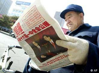 A Chinese man reads a newspaper which features a story about China's new Communist Party leader Hu Jintao, right, and his predecessor Jiang Zemin, left, while sitting on his tricycle, in Beijing Monday Nov. 18, 2002. China's media have been giving Jiang and Hu equal coverage after last week's leadership change, reflecting Jiang's continuing influence