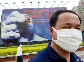 A man wears a mask to protect himself against the SARS virus, in front of a SARS billboard in Beijing Monday May 5, 2003. The billboard reads: The SARS virus will be surely be conquered by our government under the leadership of the Communist Party of China. China's government was criticized by the World Health Organization for initially covering up the SARS crisis and failing to take effective action to prevent it from worsening. (AP Photo/Greg Baker)