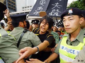 Police officers restrain activist Leung Kwok-hung, center, as he tries to advance towards a venue where Hong Kong's Chief Executive Tung Chee-hwa attends an official flag-raising ceremony marking China's National Day, early Wednesday, Oct. 1, 2003. Some 20 pro-democracy activists scuffled with police  while demanding an end to one-party rule by China's Communists. The banner  reads: "Atrocious regime stinks for 10,000 years." (AP Photo/Anat Givon)